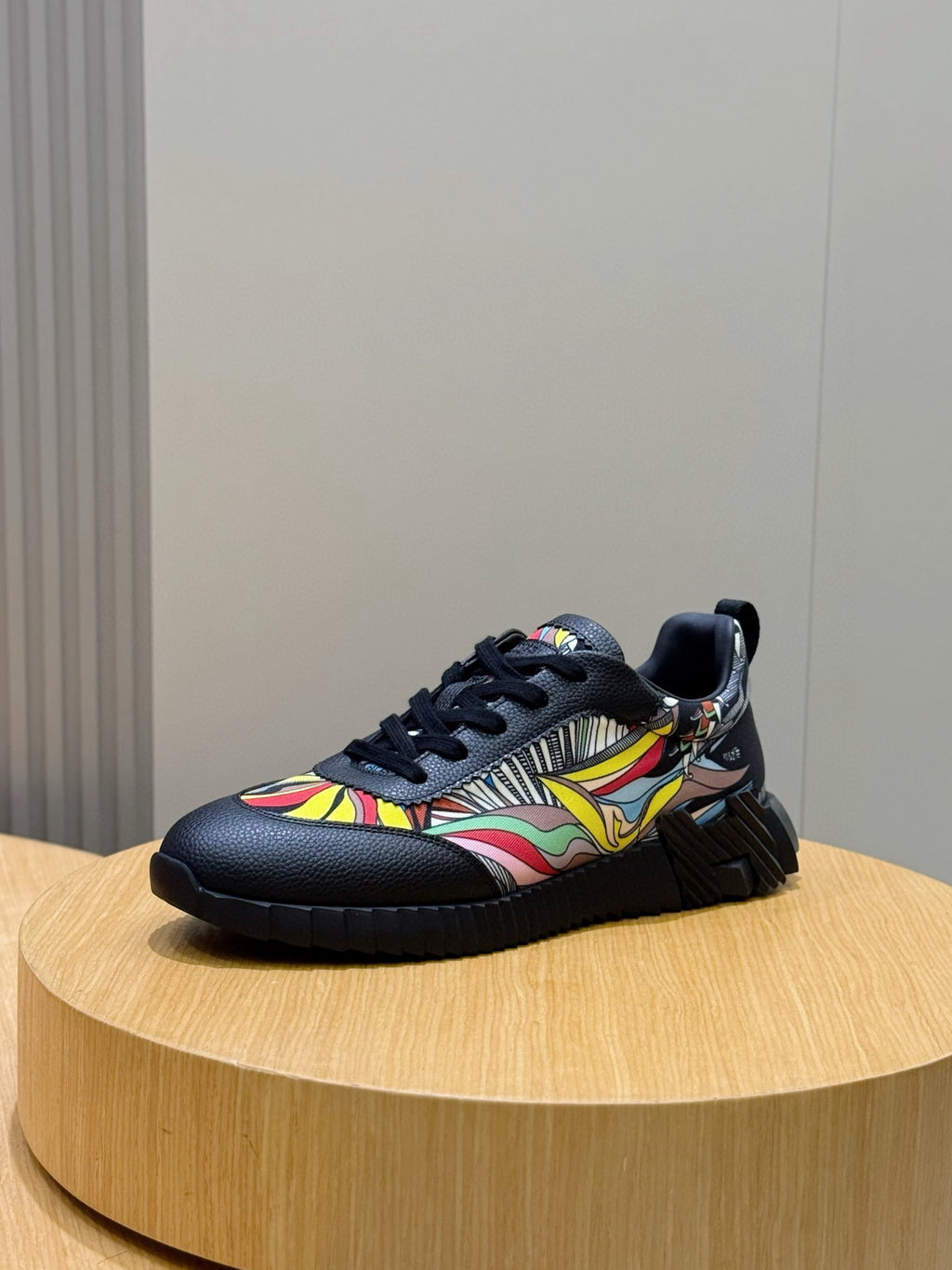Black unisex lace-up sneaker with multicolor wave graphic and cushioned sole.