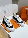 Hermes unisex sneakers, black and white with white laces and textured rubber sole.