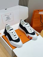 Hermes unisex sneakers, black and white with white laces and textured rubber sole.