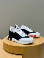 Hermes unisex sneakers, black and white with white laces and an orange side detail.