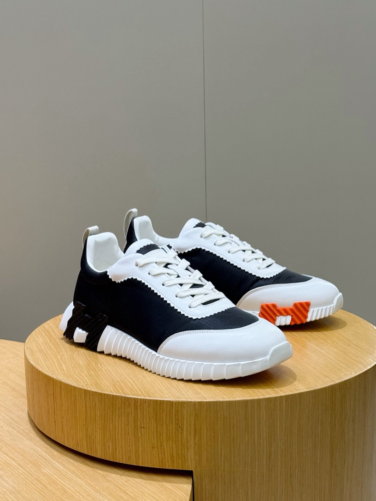 Hermes unisex sneakers, black and white with white laces and an orange side detail.
