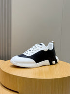 Hermes unisex sneakers with black upper, white toe, white laces, and chunky sole.