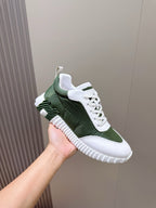 Hermes unisex sneaker on hand, dark green upper with white trim and lace-up front