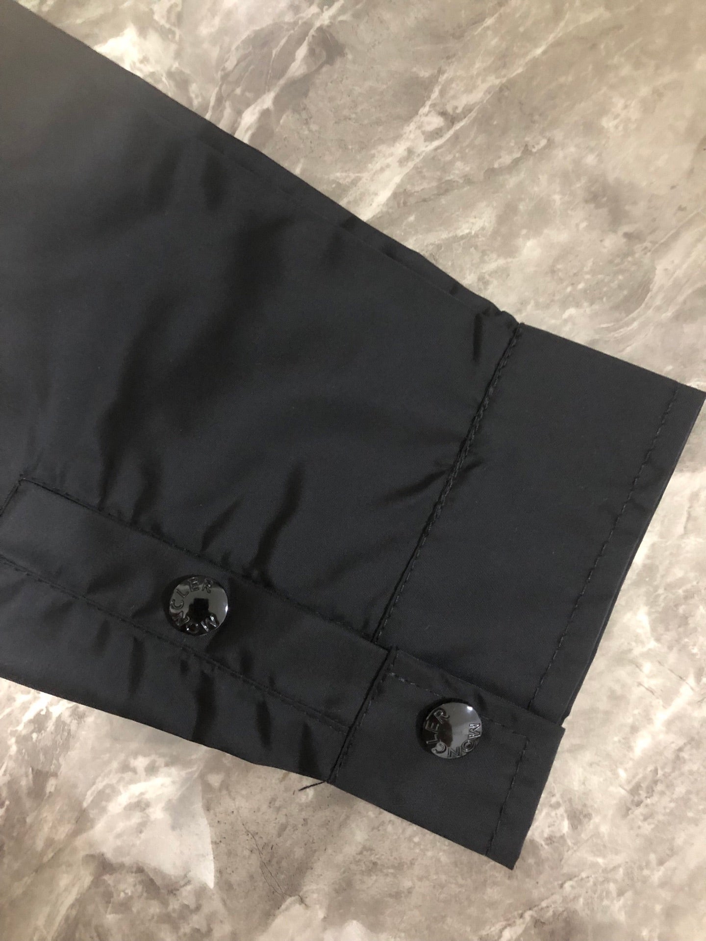 Moncler black long jacket hem with two snap buttons and stitched tab