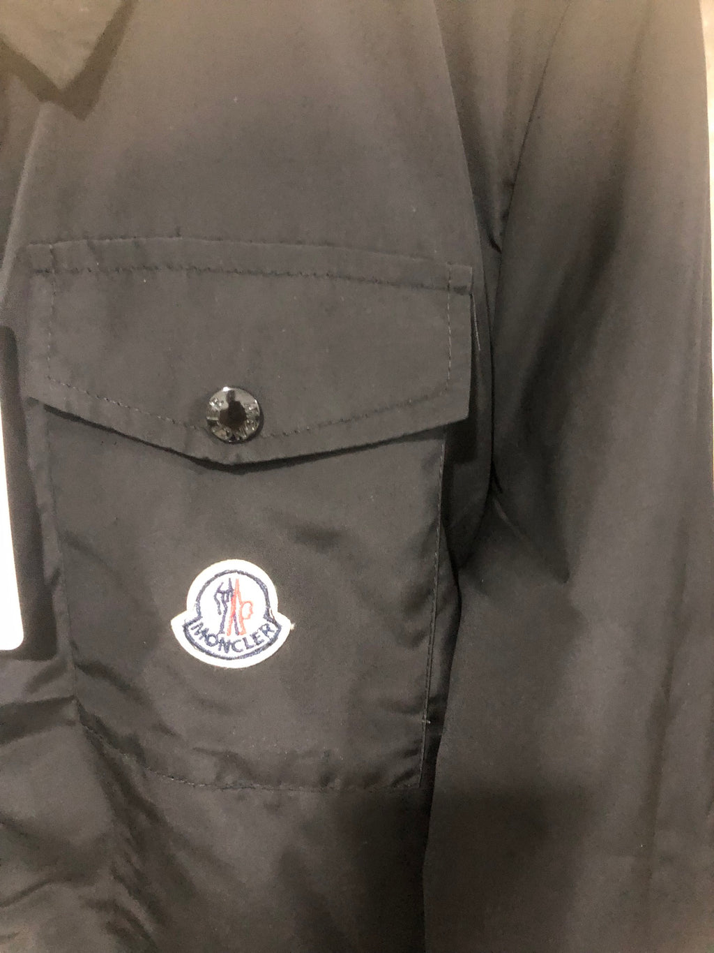 Moncler black long jacket side with buttoned pocket and circular logo patch