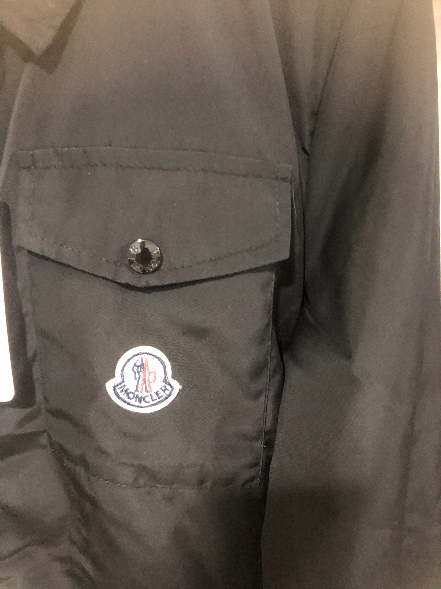 Moncler black long jacket side with buttoned pocket and circular logo patch