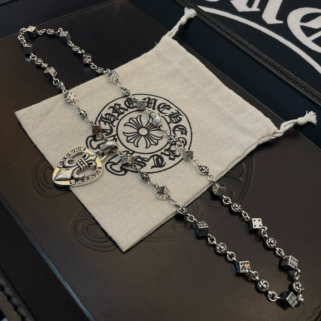 Silver-tone charm necklace draped on fabric pouch with heart pendant charm
