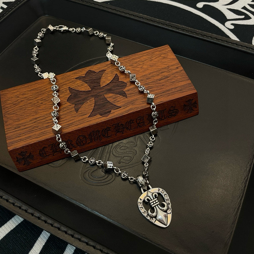 Silver-tone charm necklace on wooden box with heart pendant and floral emblem
