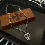 Silver-tone charm necklace on wooden box with heart pendant and floral emblem