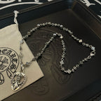Silver-tone charm necklace with heart pendant resting on dark presentation box