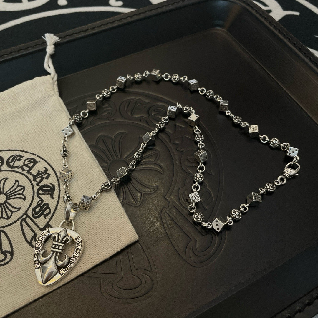 Silver-tone charm necklace with heart pendant resting on dark presentation box