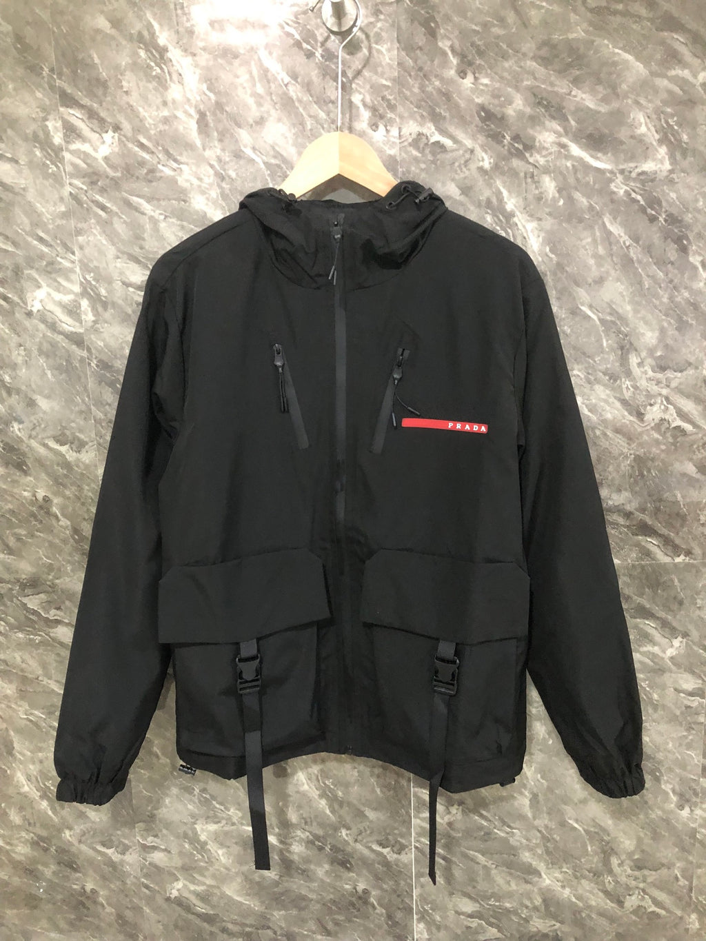 Black hooded long jacket with zip front, drawstring hem, and utility pockets
