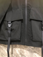 Black long jacket with hood, front utility pockets, and adjustable strap detail