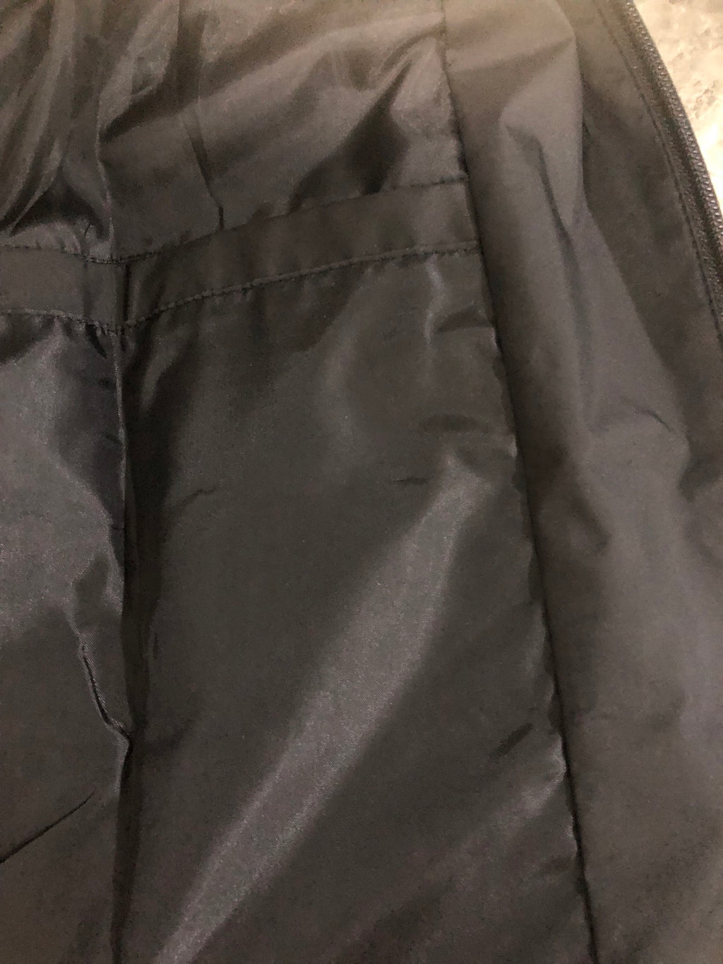 Windbreaker jacket inner pocket area, dark fabric with seams