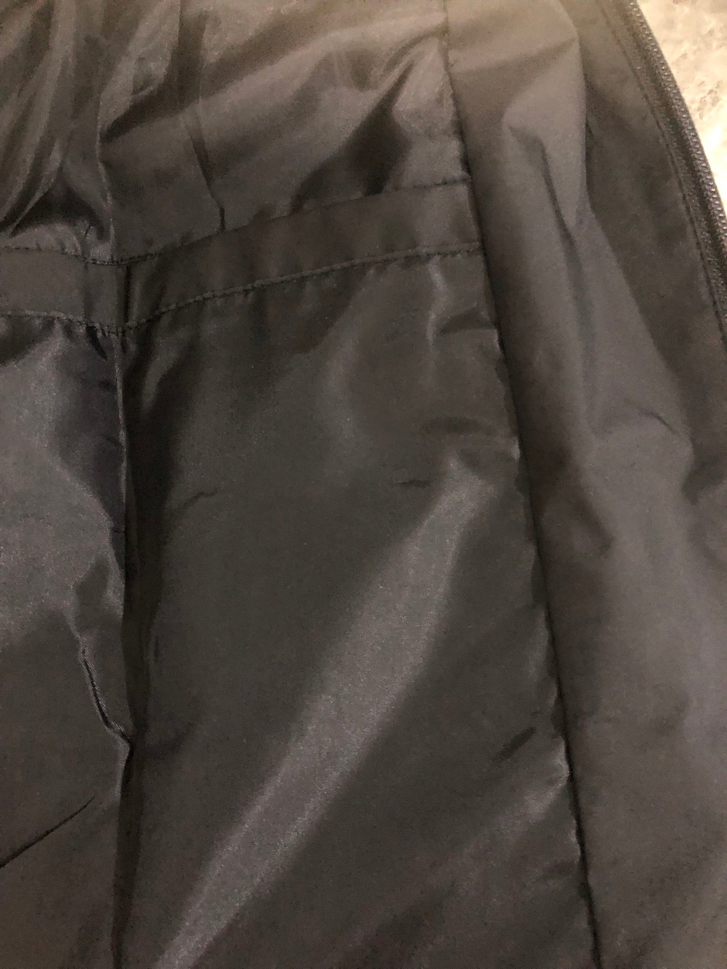 Windbreaker jacket inner pocket area, dark fabric with seams