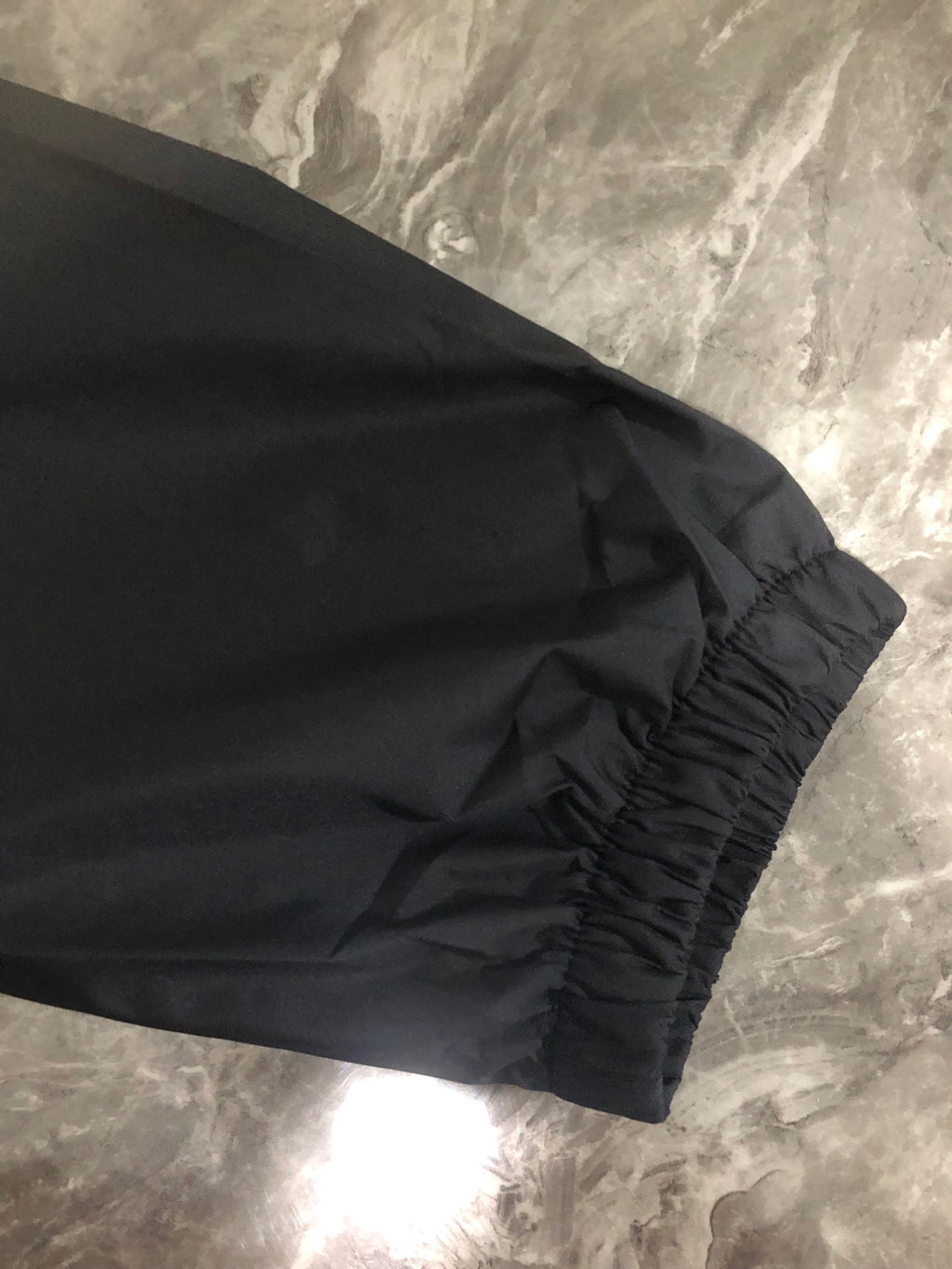 Windbreaker jacket hem and sleeve cuff, dark fabric with elastic gather