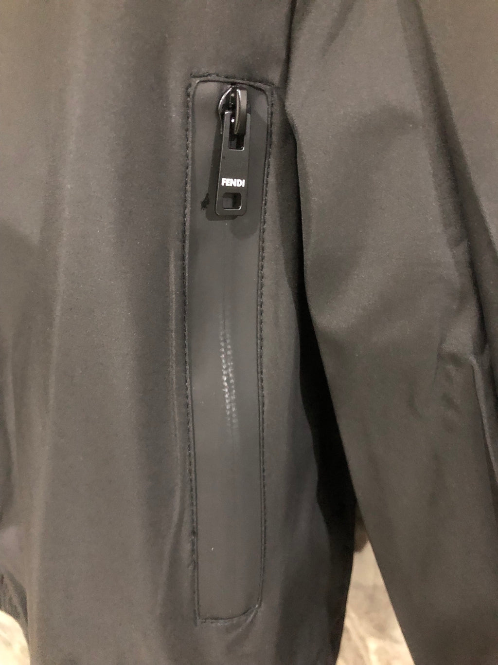 Windbreaker jacket zipper pull, dark fabric with stitched label holder