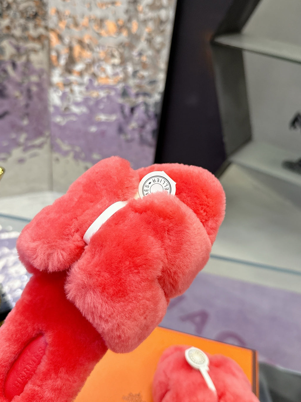 Red plush crossover slide sandal with white circular logo medallion on top strap