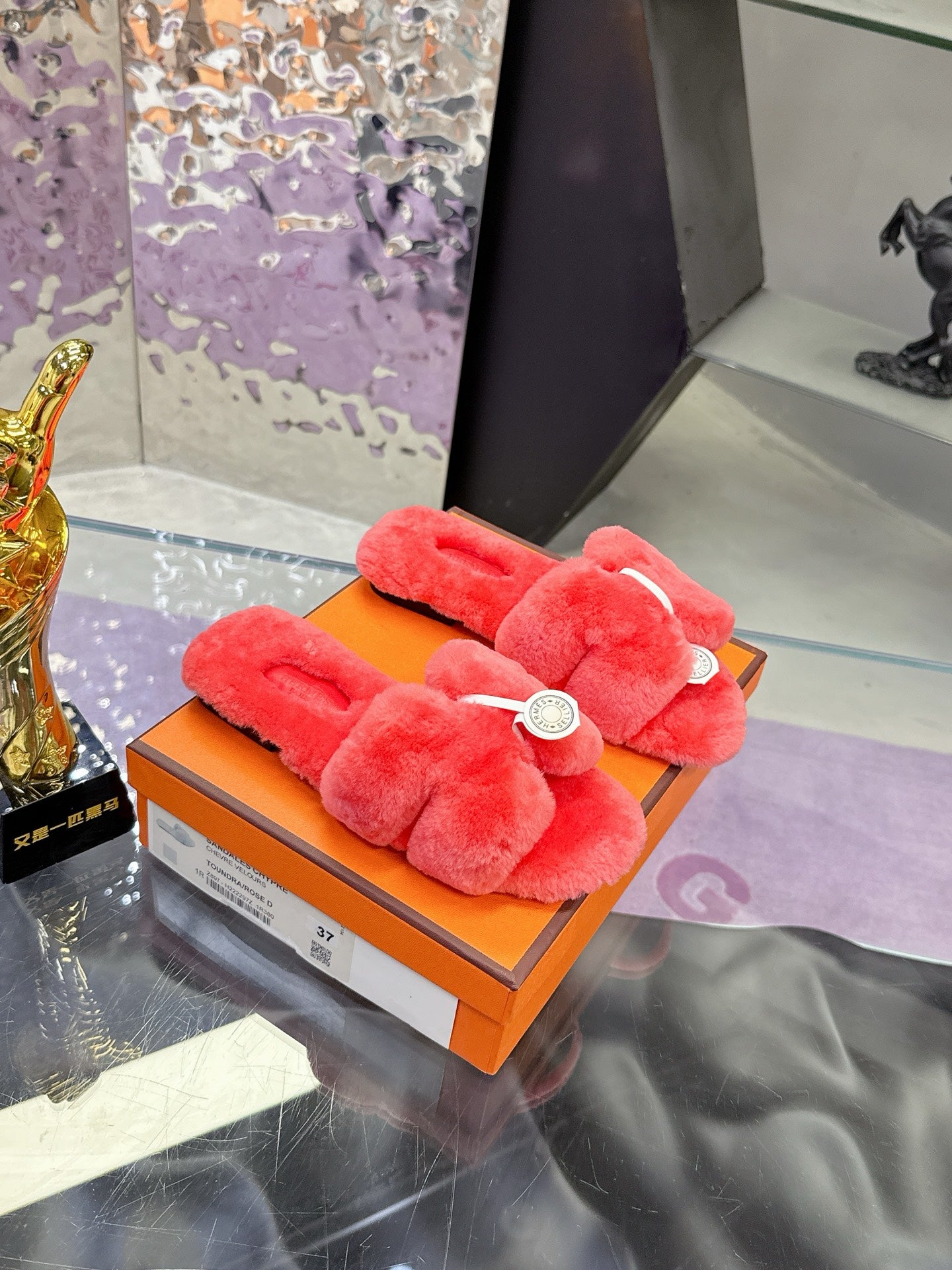 Red fuzzy slides with two wide straps and white circular logo medallion