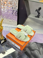 Mint green sherpa slide sandals with black sole, shown in orange gift box
