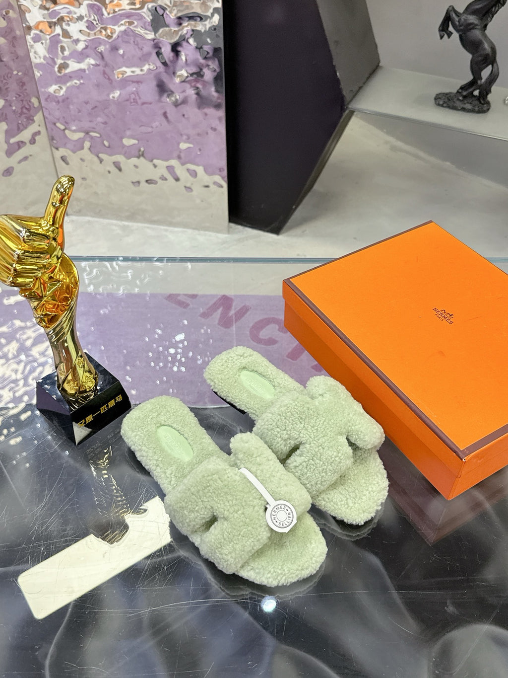 Mint green fluffy slide sandals with black outsole, shown with orange box