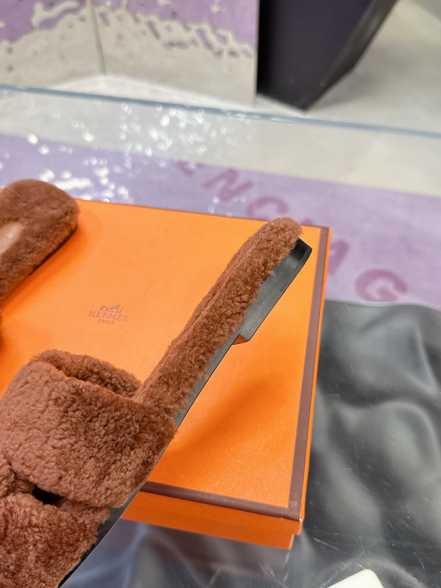 Brown plush slide sandals with wide strap, close-up of outsole edge