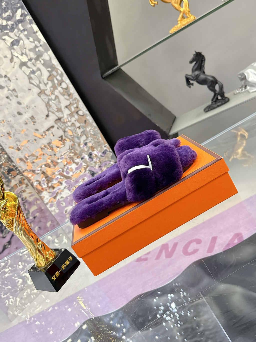 Hermes ladies purple faux-fur slides with bow detail, resting on orange box