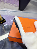 Side view of white plush slide sandal on orange box, strap with logo patch