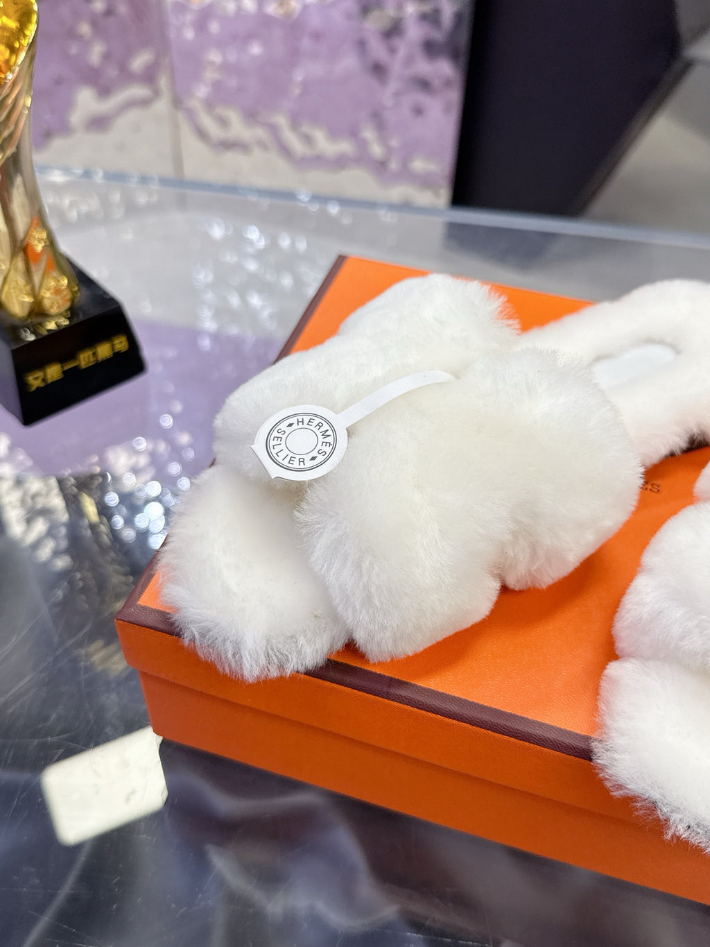 Close-up of white plush slide sandal strap with circular logo patch