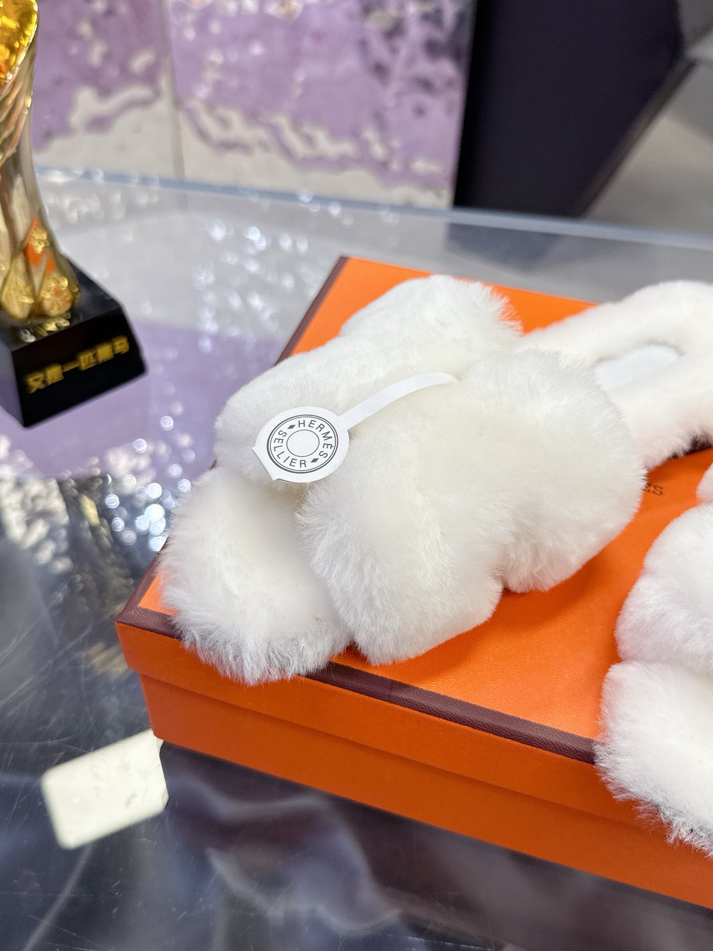 Close-up of white plush slide sandal strap with circular logo patch