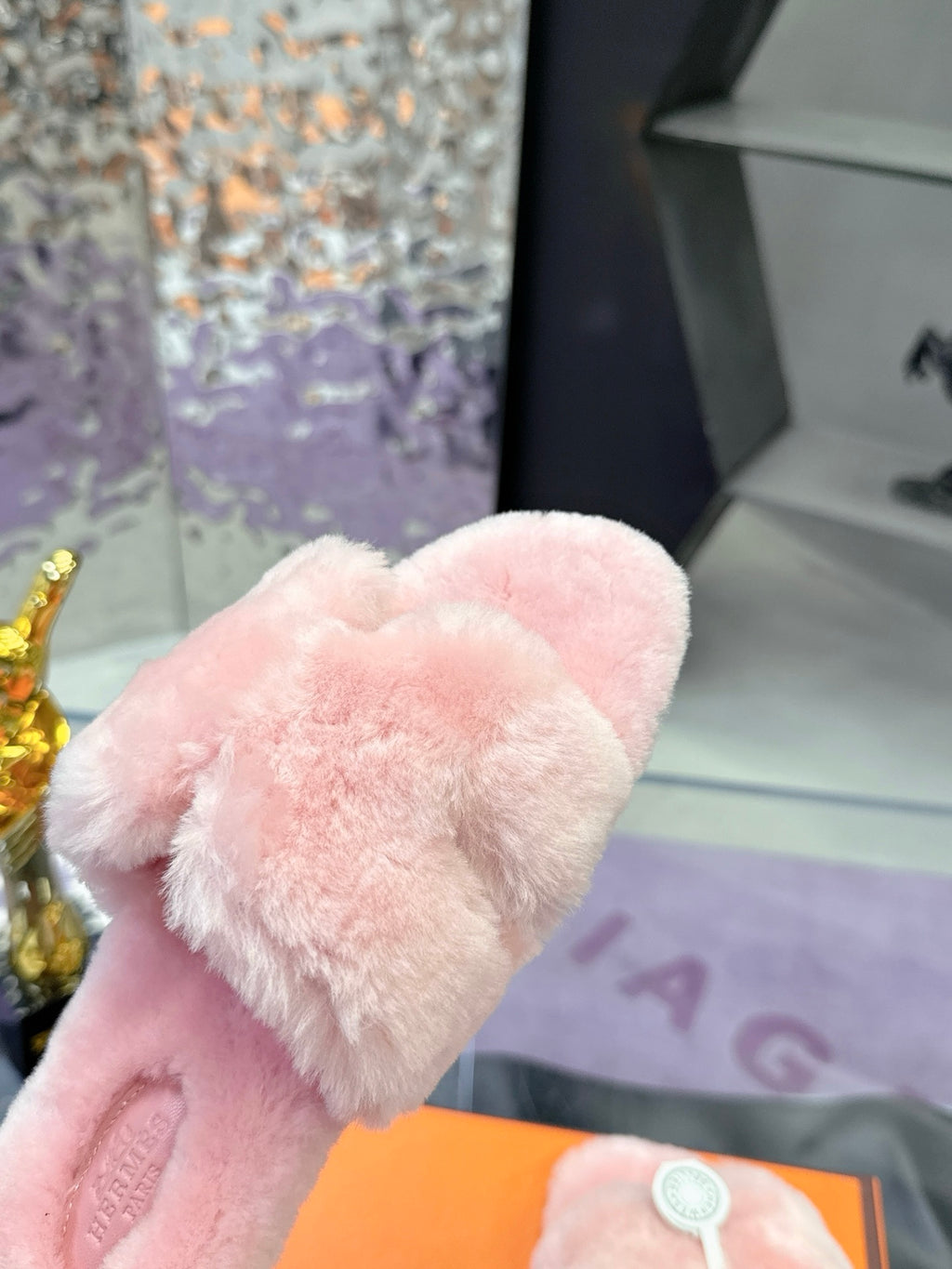 Pink faux-fur strap with embossed logo medallion on slide sandal