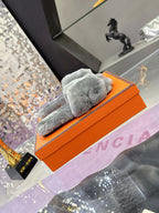 Hermes luxury shoes, grey plush slide viewed from side on orange box