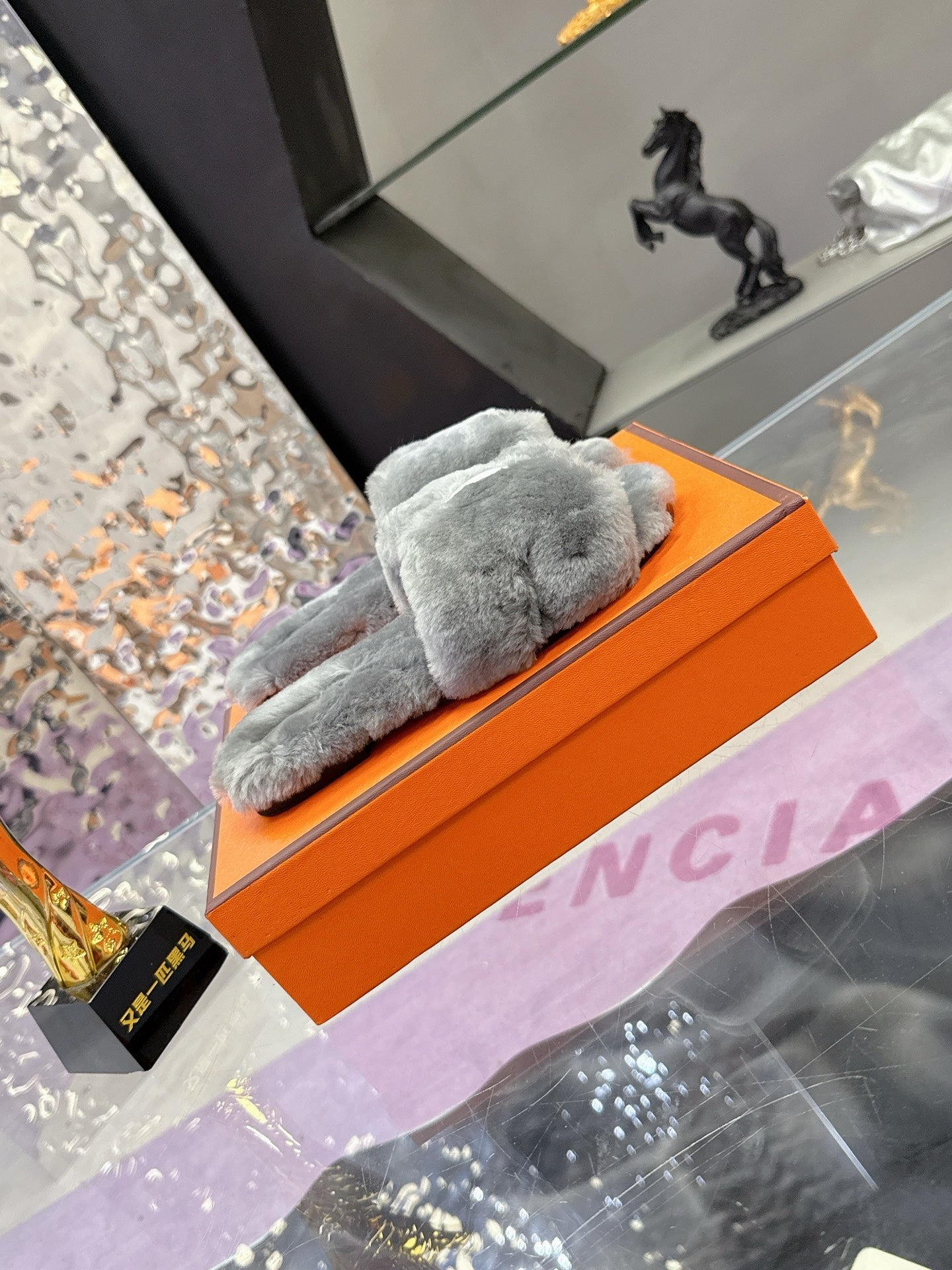 Hermes luxury shoes, grey plush slide viewed from side on orange box