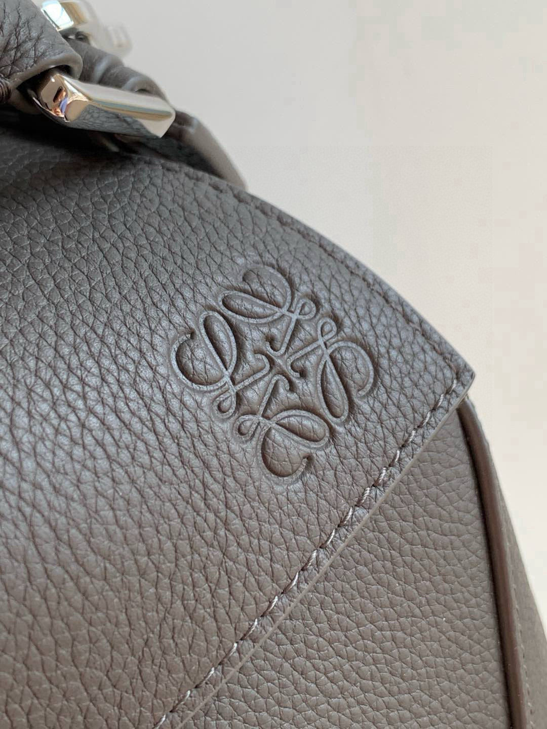 Loewe men's bag close-up of embossed logo on textured dark gray leather