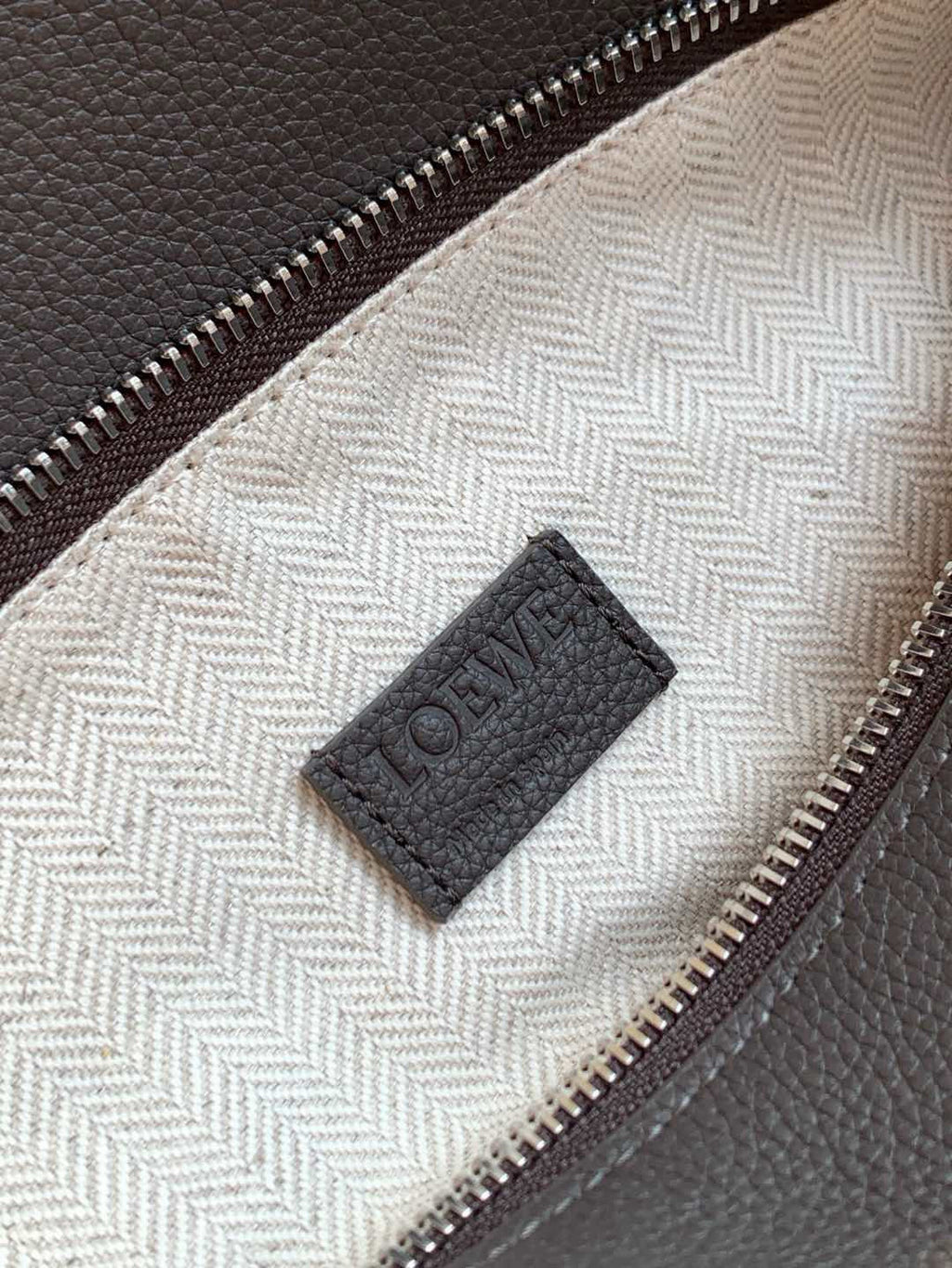 Loewe men's bag lining close-up with Loewe patch tag near zipper