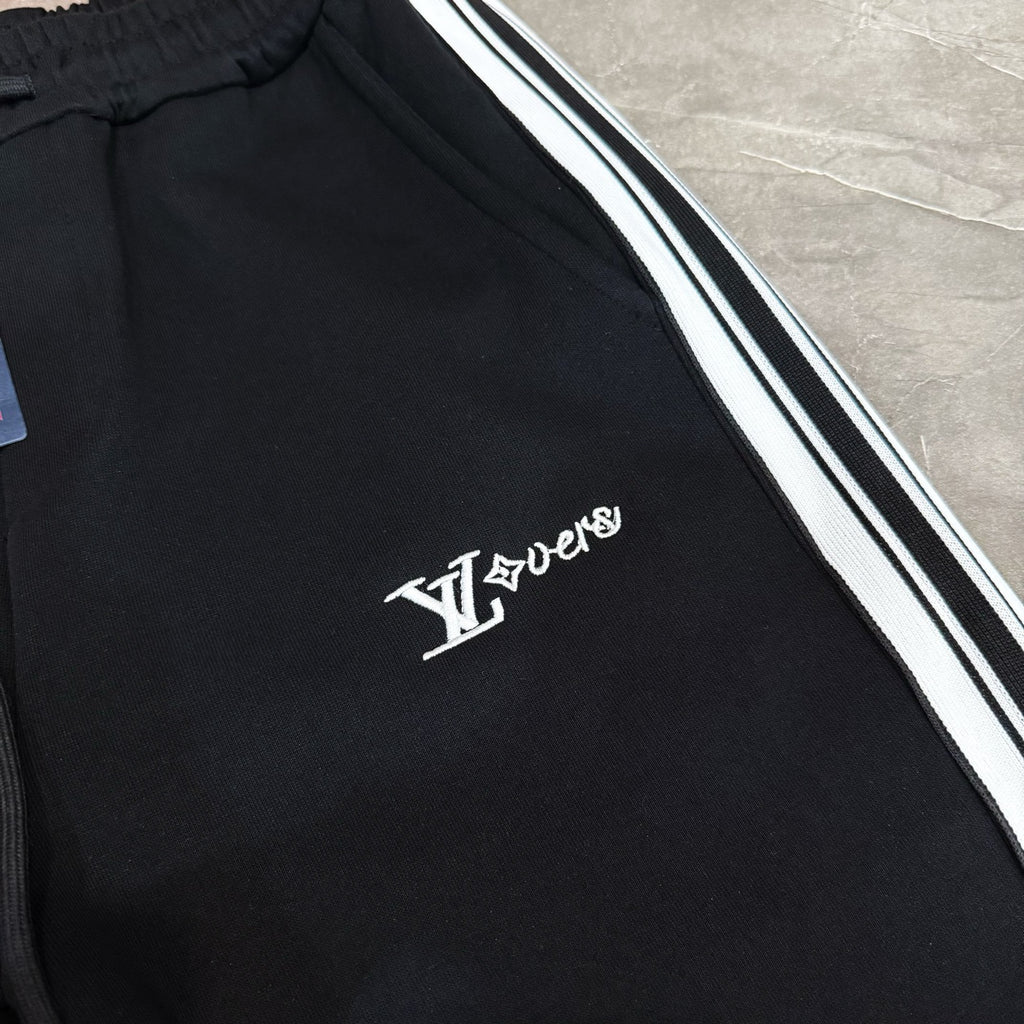 Black track pants with white and black side stripes and LV logo