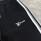 Black track pants with white and black side stripes and LV logo