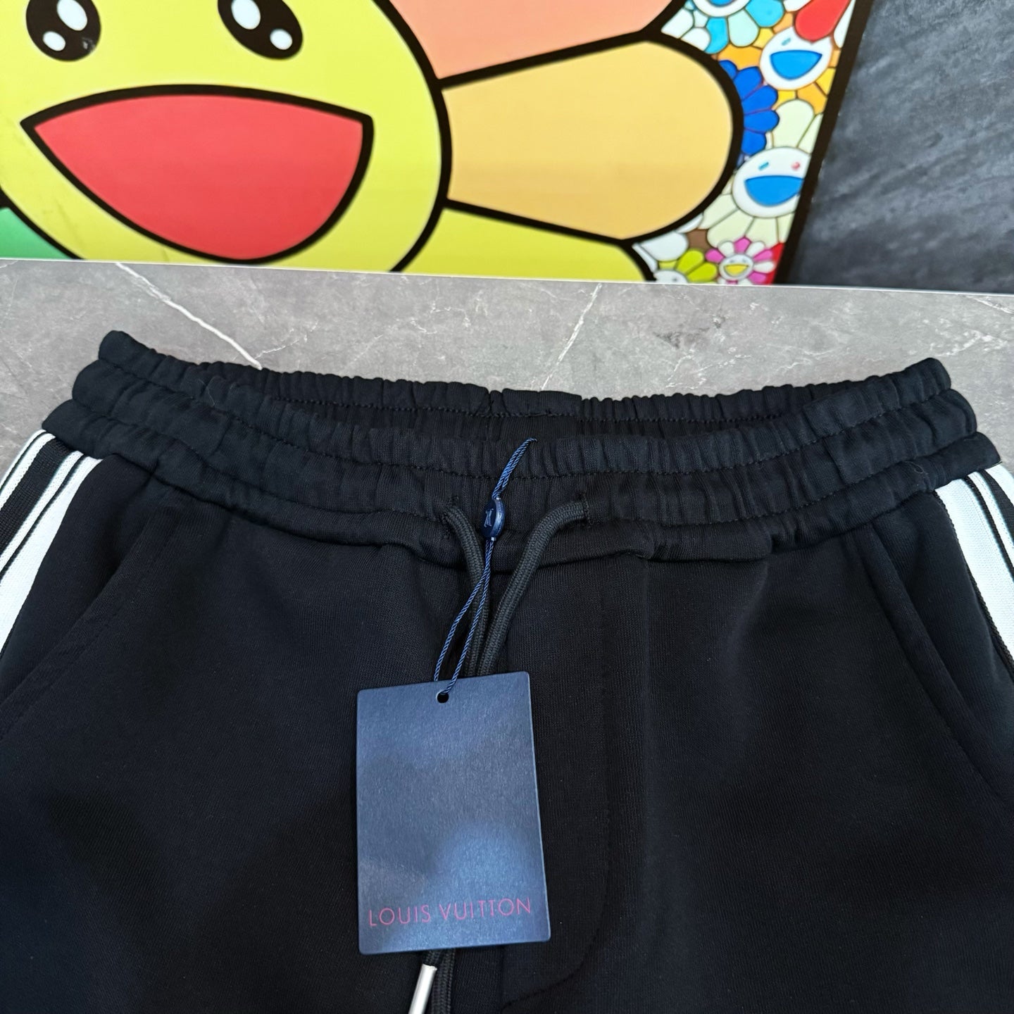 Black jogger pants with elastic waistband, drawstring, and attached Louis Vuitton tags
