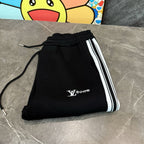 Black track pants folded with elastic waistband, drawstring, and side stripe detail