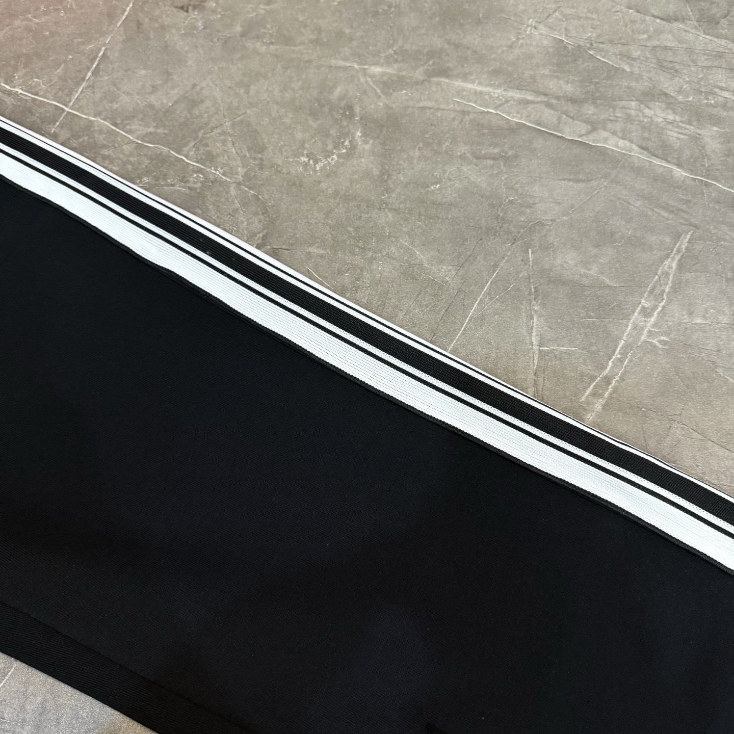 Black track pants with triple white-and-black side stripe detail