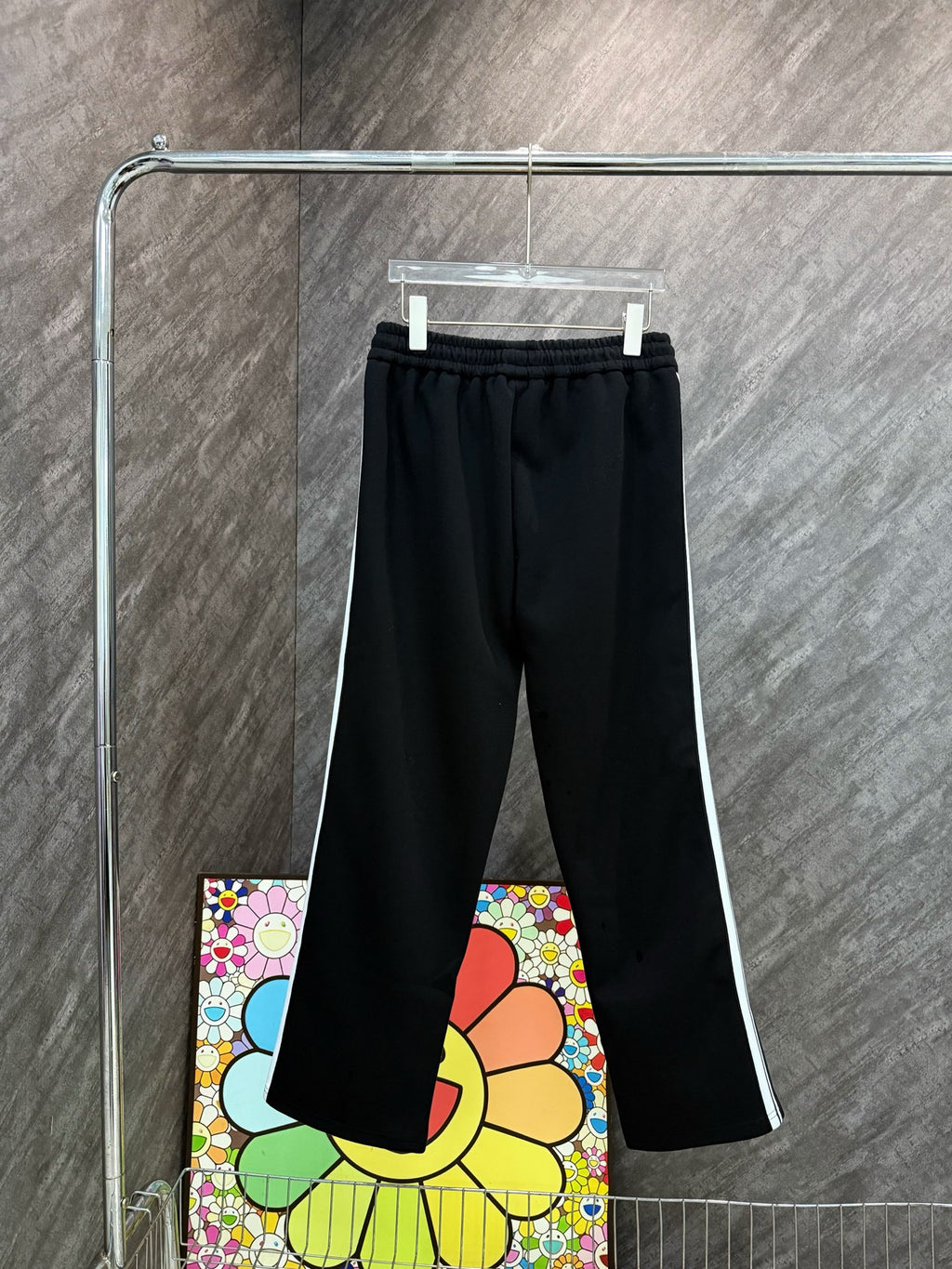 Black track pants with elastic waistband, drawstring, and colorful cartoon side print