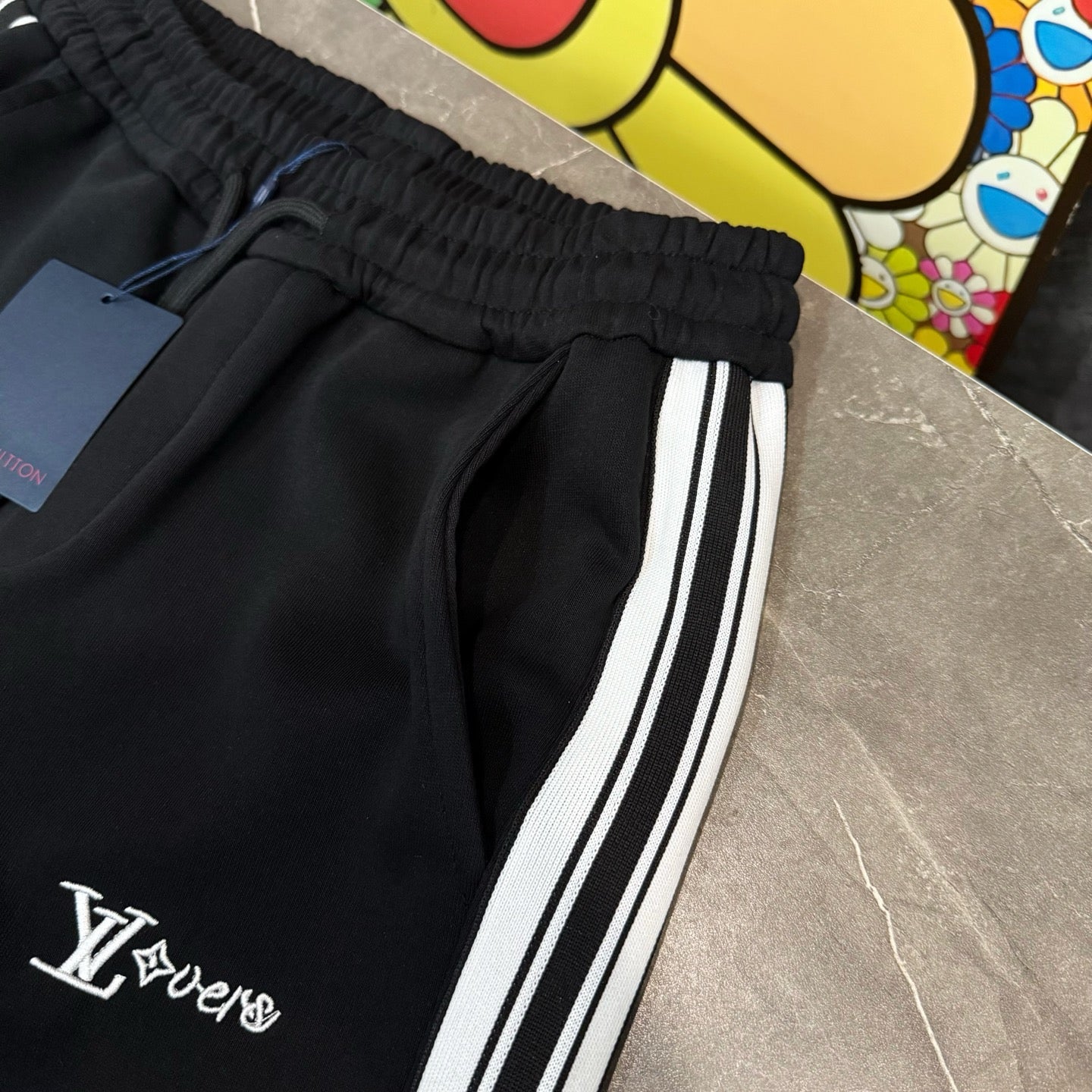 Black jogger pants with elastic waistband, drawstring, and side stripe logo