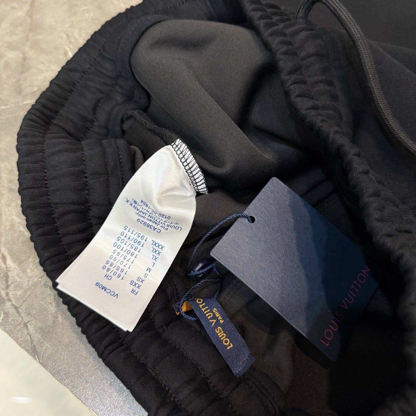 Black jogger pants with elastic waistband, inner fabric, and attached product tags