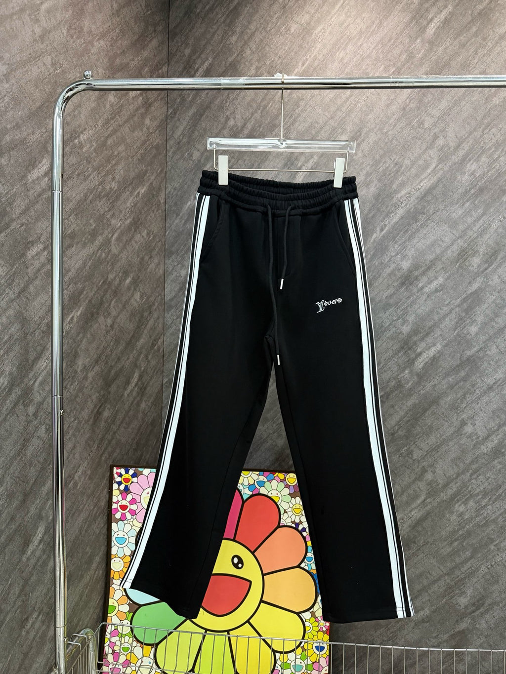 Black track pants with elastic waistband, drawstring, and logo at thigh