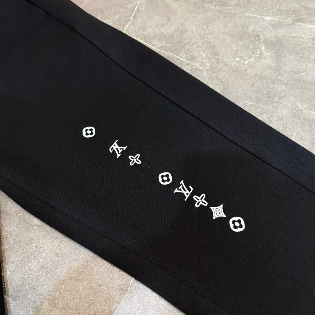 Louis Vuitton black pants detail with small LV and quatrefoil logos