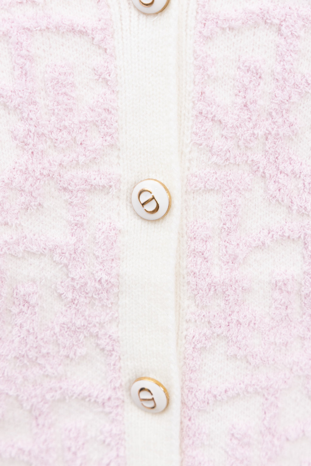 Cardigan button detail on pale pink textured knit with white placket and logo buttons