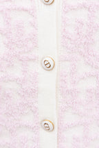 Cardigan button detail on pale pink textured knit with white placket and logo buttons