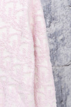 Pale pink textured knit cardigan fabric close-up