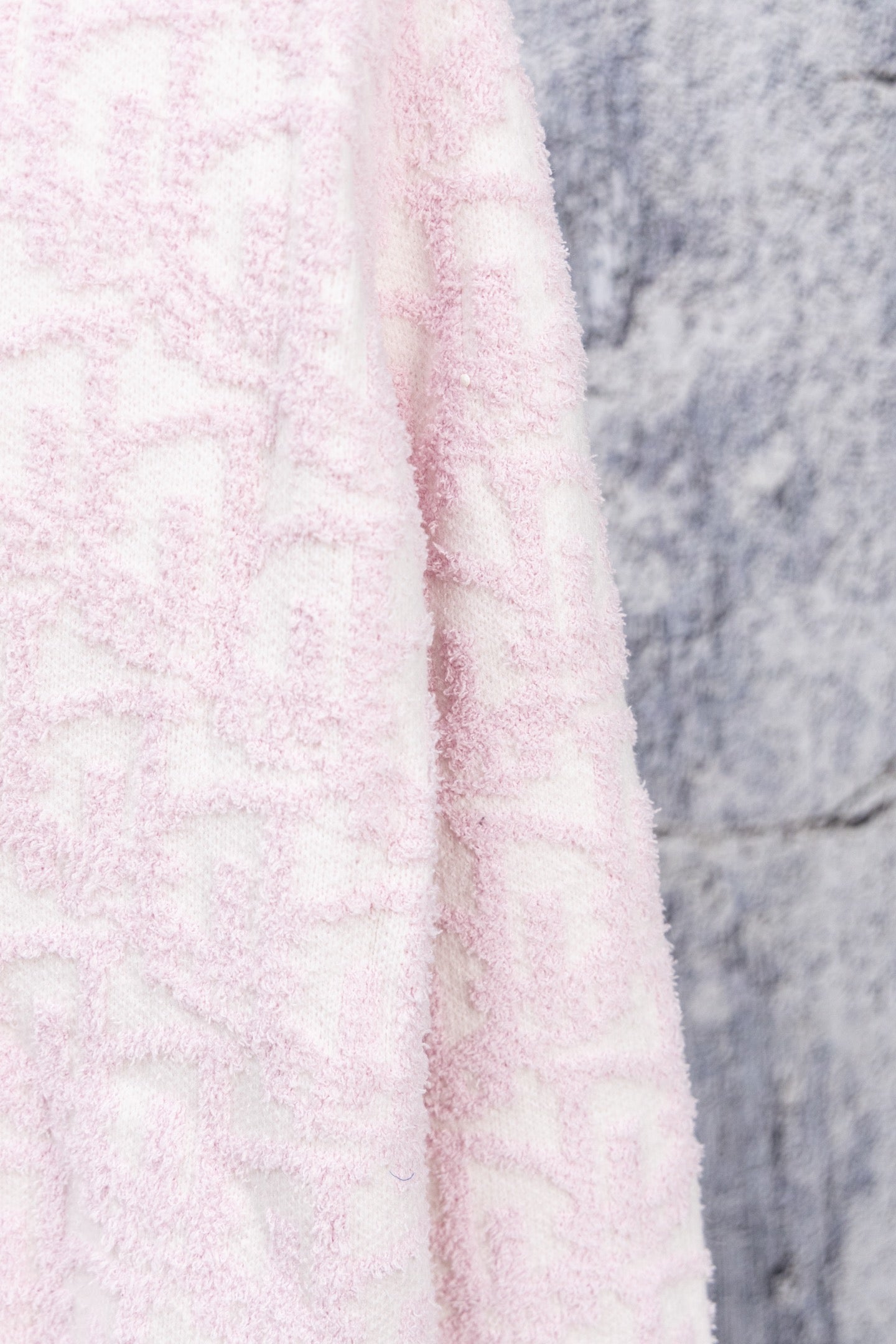Pale pink textured knit cardigan fabric close-up