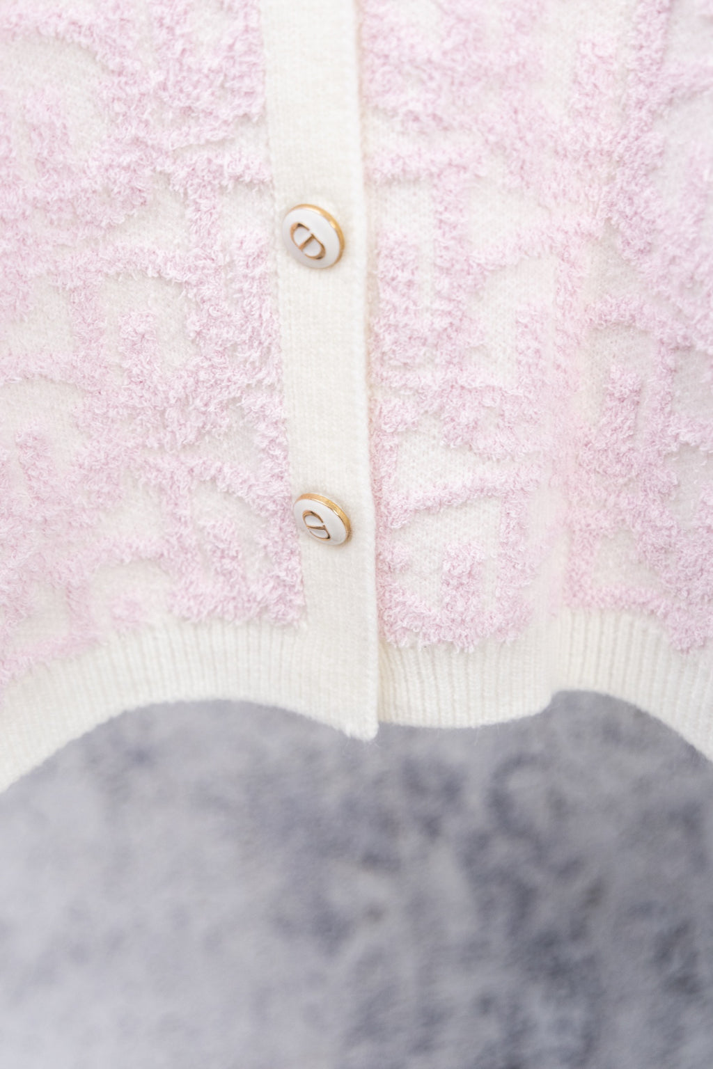 Pale pink textured cardigan with white ribbed hem and button placket
